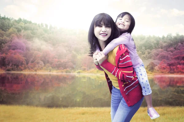 Girl piggyback ride with her mother — Stock Photo, Image