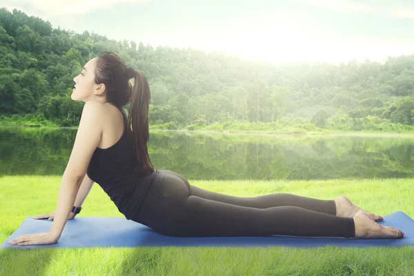 Mujer árabe practicando yoga cerca del lago —  Fotos de Stock