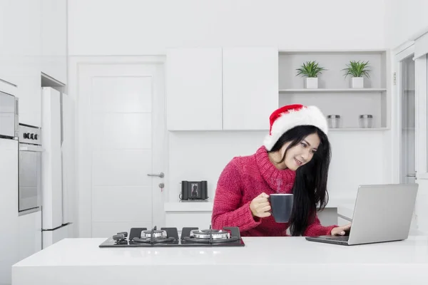 Mujer joven usando un ordenador portátil en la cocina — Foto de Stock