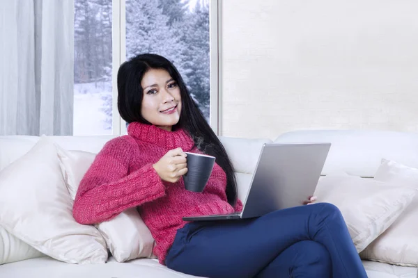 Vrouw met laptop en hete thee ontspannen — Stockfoto