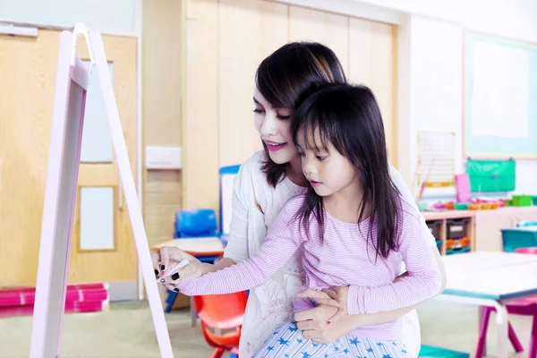 Mała dziewczynka nauka pisać z jej nauczyciel — Zdjęcie stockowe