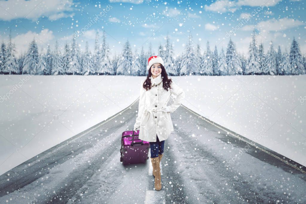 Pretty woman with suitcase on the snowy road