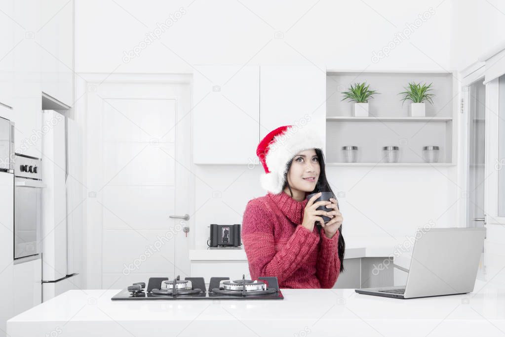 Pretty woman wears Santa hat in the kitchen