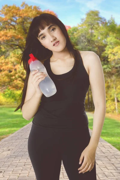 Arabian woman holds bottle in the park — Stock Photo, Image