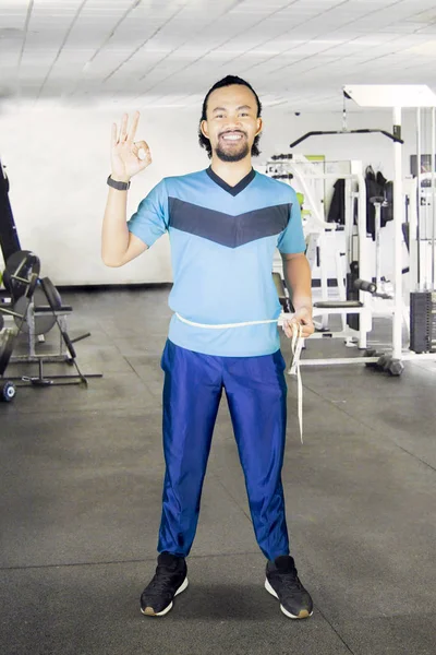 African man measuring waistline in the fitness center — Stock Photo, Image