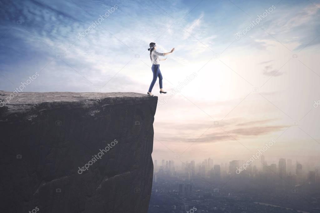 Businesswoman walks blindfolded on the cliff