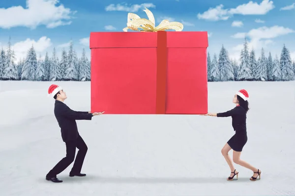 Business people lifting a big presents box — Stock Photo, Image
