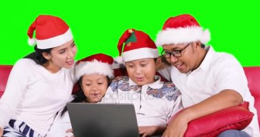 Aile Noel Baba şapkası ile kanepede dizüstü bilgisayar kullanmak