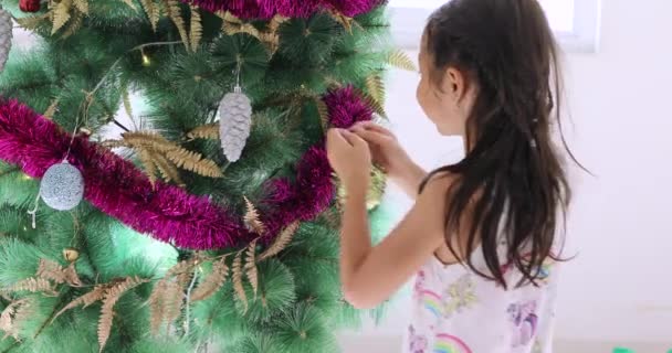 Schattig klein meisje opknoping op Christmas tree ornament — Stockvideo