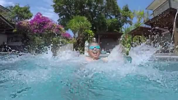 Chico excitado salpicando agua en la piscina — Vídeo de stock