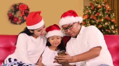 Aile ile Noel Baba şapkası kullanma smartphone evde