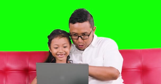 Веселые отец и дочь использовать ноутбук на диване — стоковое видео