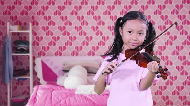 Schattig meisje spelen een viool in slaapkamer — Stockvideo