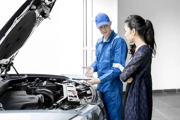 Young mechanic giving repair cost to his client — Stock Photo, Image