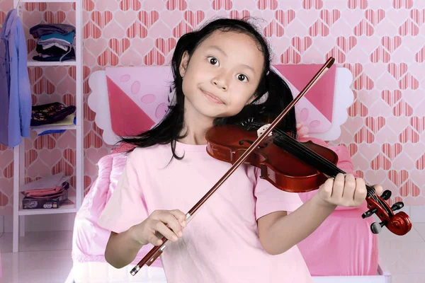 Malá holčička hraje na housle v ložnici — Stock fotografie