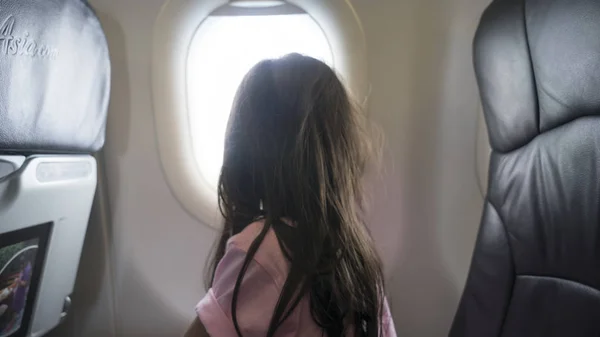 Mädchen schaut aus Flugzeugfenster nach draußen — Stockfoto