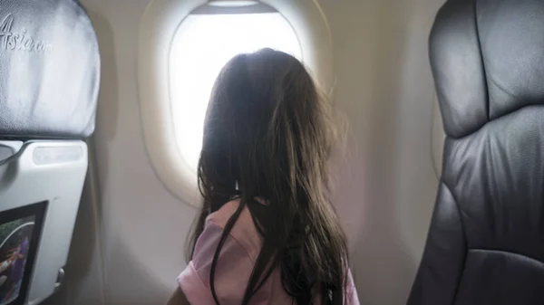 Ragazza guardando fuori dalla finestra dell'aeroplano — Foto Stock