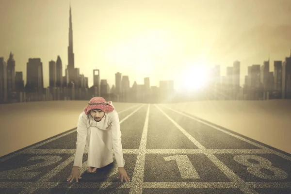 Арабский бизнесмен стоит на коленях на треке — стоковое фото
