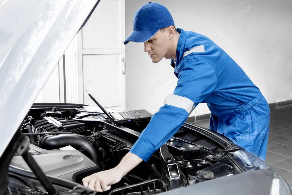 American mechanic checking car with a laptop