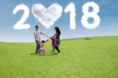 Genç aile birlikte çayırda gülüyor