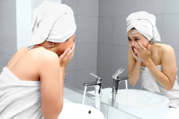 Jeune femme se lave le visage avec de l'eau — Photo