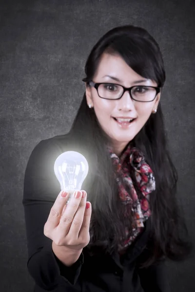 Schöne Geschäftsfrau zeigt eine helle Glühbirne — Stockfoto