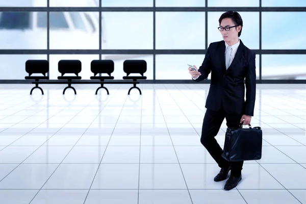 Uomo d'affari asiatico con smartphone in aeroporto — Foto Stock