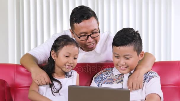 若い父親が自宅のリビング ルームで彼らの目を閉じて ラップトップ上の不適切なコンテンツから子供を保護します — ストック動画
