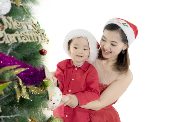 Mutter schmückt Weihnachtsbaum mit ihrem Sohn — Stockfoto