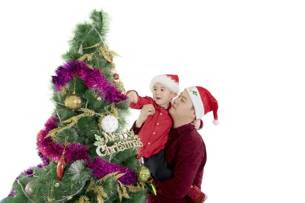 Vater hilft seinem Sohn beim Weihnachtsbaum schmücken — Stockfoto