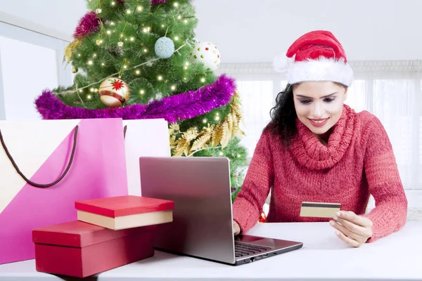 Menina bonita detém cartão de crédito perto da árvore de Natal — Fotografia de Stock