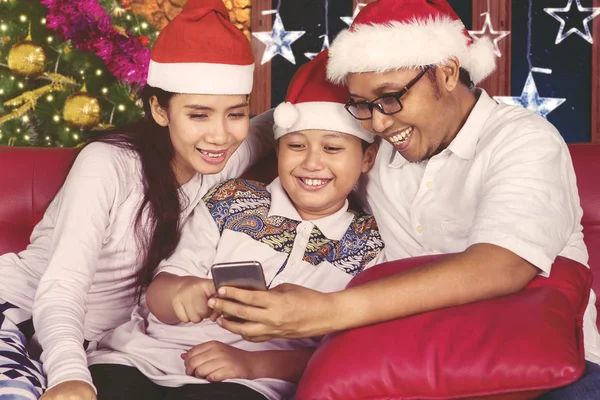 Familia feliz usando un smartphone en Navidad —  Fotos de Stock