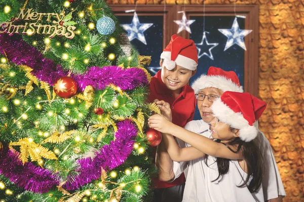 Les enfants et leur grand-père jouent avec l'arbre de Noël — Photo