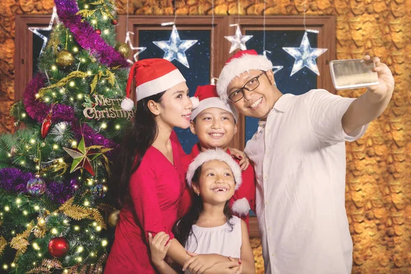 Familia alegre tomando fotos con el árbol de Navidad —  Fotos de Stock