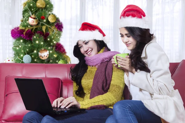 Beautiful women with laptop near Christmas tree — Stock Photo, Image