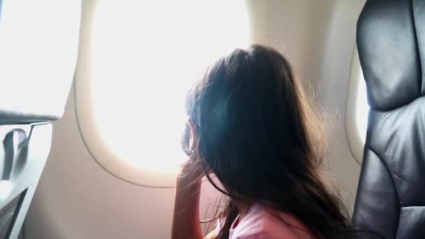 Šťastná holčička se dívá z okna v letadle při tleskat při letu na dovolenou