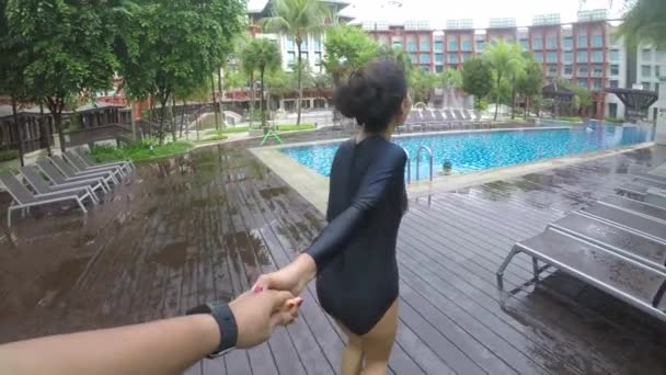 若い女性が男の手を引いて スイミング プールに向かう彼のビデオ映像 — ストック動画