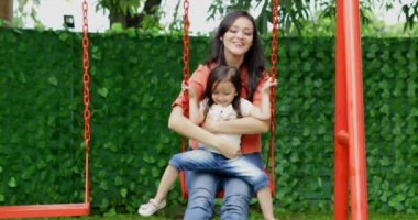 Mutlu genç anne ve kızı eğleniyor birlikte parkta, salıncakta vurdu içinde 4 k çözünürlük