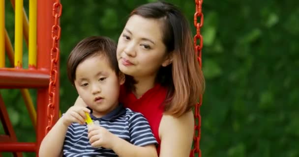 Lindo Niño Soplando Burbujas Jabón Mientras Besado Por Madre Columpio — Vídeo de stock