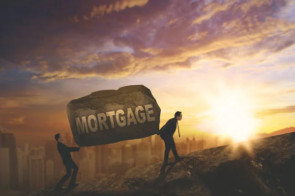 Two Asian businessmen carrying mortgage word — Stock Photo, Image