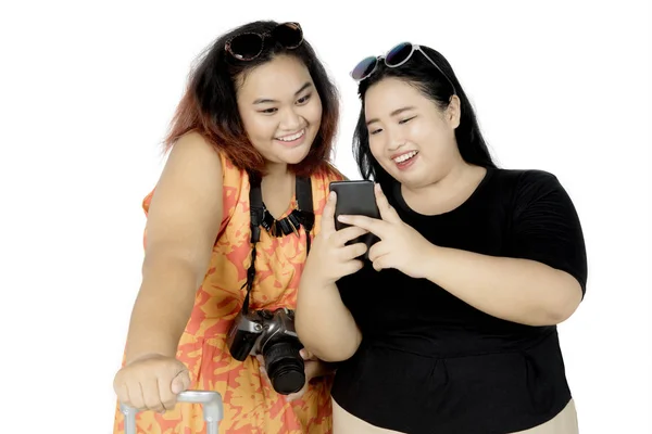 Two fat tourists using a smartphone on studio — Stock Photo, Image