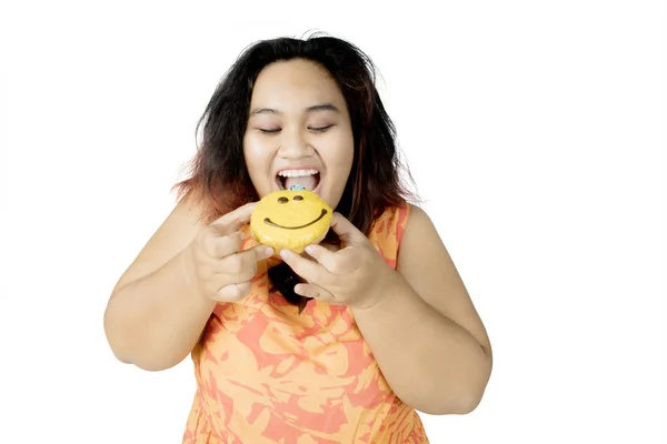 Femme en surpoids manger un beignet en studio — Photo