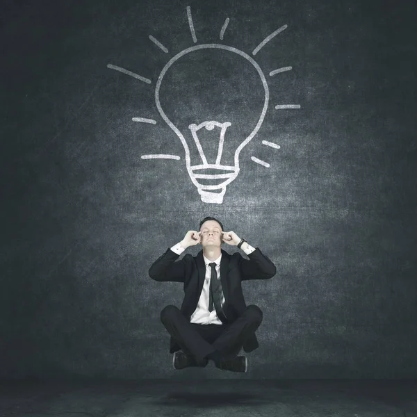 Male manager levitating under light bulb — Stock Photo, Image