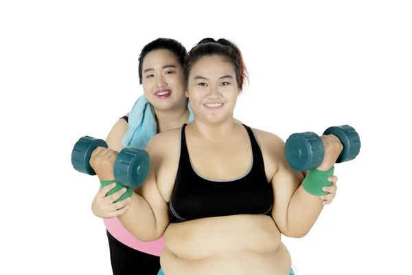 Mulher gorda e sua amiga levantando halteres — Fotografia de Stock