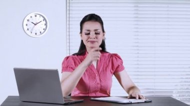 Süre düşünme fikir ofiste çalışan ve laptop üstünde okul sırası ile bir evrak üzerinde yazma genç bir kadın işçi
