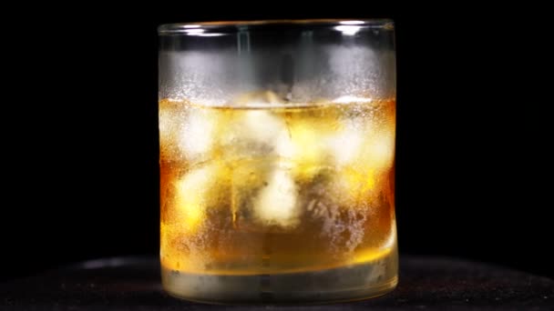 Closeup Whisky Glass Ice Cube Spinning Table Shot Dark Background — Stock Video