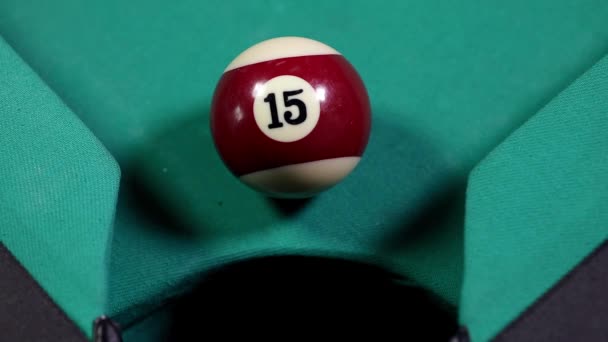 Gros plan d'une boule de billard avec le numéro quinze, tombant dans le trou de la table de billard 
