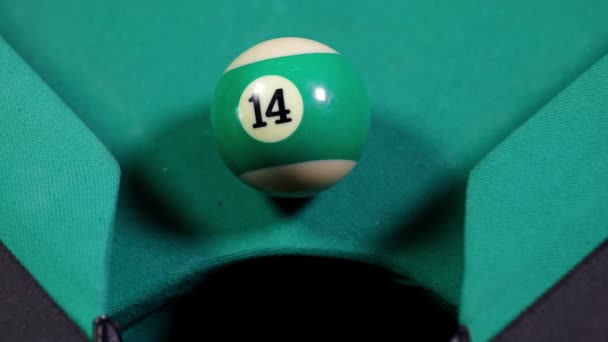 Gros plan de la boule de billard numéro 14 avec la couleur verte tombant dans le trou de la table 