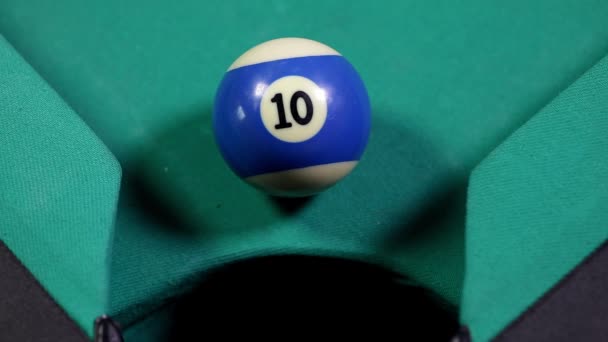 Gros plan d'une boule de billard numéro 10 de couleur bleue, tombant dans le trou de la table de billard 