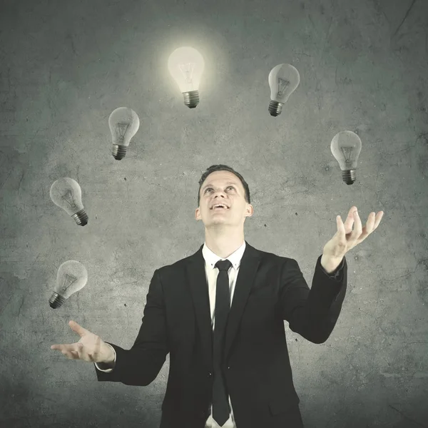 Young entrepreneur juggling many light bulbs — Stock Photo, Image